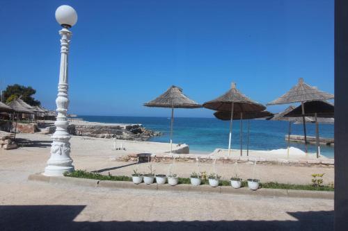 a street light next to a beach with umbrellas at Hotel Artur in Ksamil