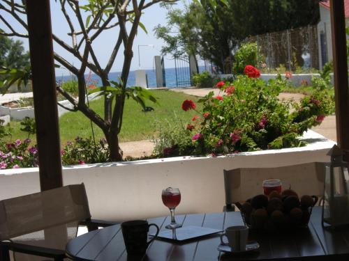 a table with a glass of wine and flowers at Nicholas Waves Beach Studios in Lardos