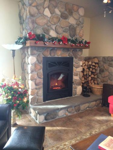 a living room with a stone fireplace with christmas decorations at Auberge Sous les Arbres in Gaspé
