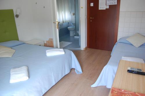 a room with two beds and a bathroom with a toilet at Hotel Irene in Lignano Sabbiadoro