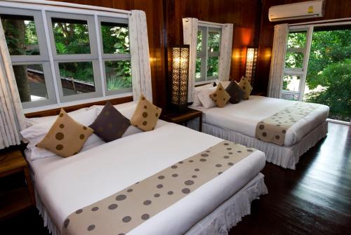 two beds in a room with windows at Rain Forest Resort in Ban Pak Yang