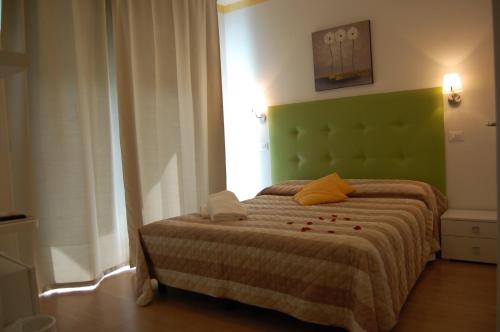a bedroom with a bed with a green headboard at Hotel Irene in Lignano Sabbiadoro