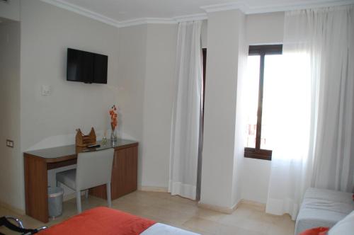 ein Wohnzimmer mit einem Schreibtisch und einem TV an der Wand in der Unterkunft Triana L in Sevilla