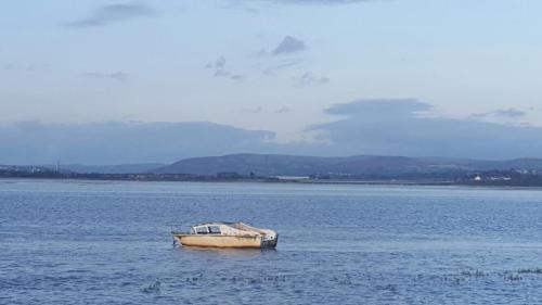 a boat sitting in the middle of the water at Waters Edge in Penclawdd
