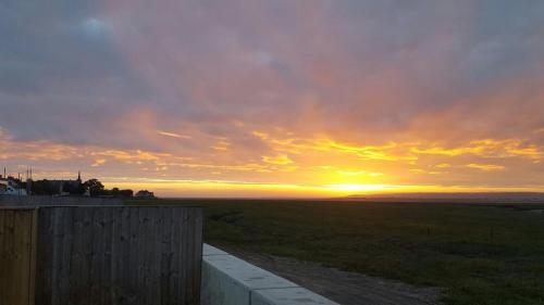 a sunset over a field with a wooden fence at Waters Edge in Penclawdd