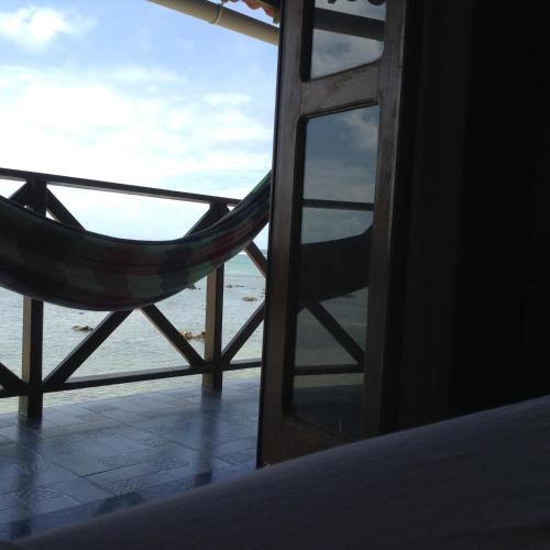 a window with a hammock looking out at the ocean at Pousada Tranquila in Morro de São Paulo