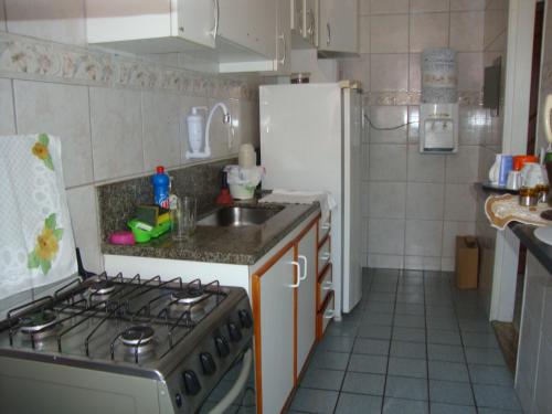 a kitchen with a stove and a sink and a refrigerator at Apto Arpoador Próximo Praia VV in Vila Velha