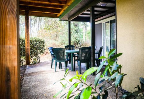 eine Terrasse mit Stühlen und einem Tisch auf einer Veranda in der Unterkunft Village Vacances Les Genêts in Léon