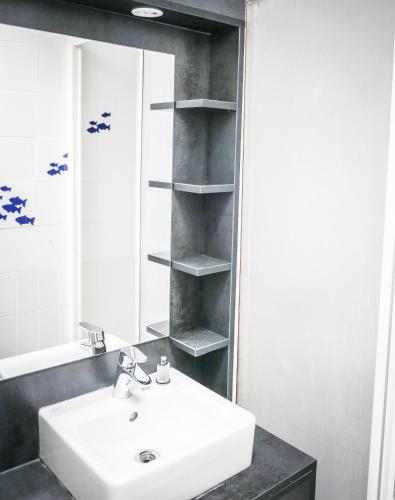 une salle de bain avec un lavabo et un miroir dans l'établissement Village Vacances Les Genêts, à Léon