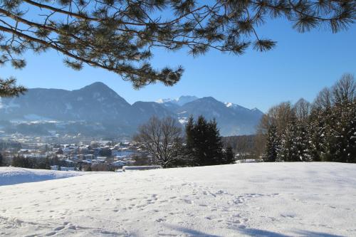 a snow covered hill with a city and mountains in the background at Pension Christoph in Kramsach