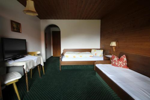 a room with two beds and a flat screen tv at Pension Christoph in Kramsach
