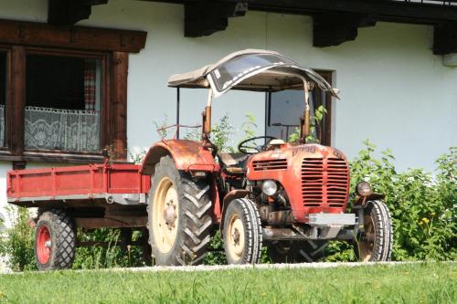 an old red tractor parked in front of a house at Pension Christoph in Kramsach