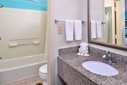 a bathroom with a sink and a toilet and a mirror at Howard Johnson by Wyndham Houston Heights Downtown in Houston