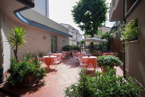 an outdoor patio with tables and chairs and an umbrella at Hotel Ricchi in Rimini