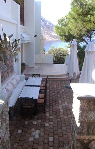 a patio with tables and umbrellas and a view of the ocean at Oasis Hotel in Masouri