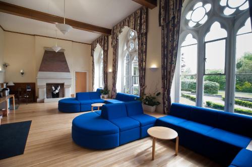 a living room with blue furniture and large windows at Hinsley Hall in Leeds