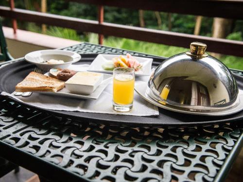 Selborne Golf Estate, Hotel & Spa في بنينغتون: طاولة سوداء عليها صينية طعام وكأس عصير برتقال