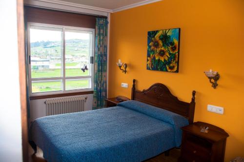 Un dormitorio con una cama azul y una ventana en Hospedaxe Carragal, en Ribadeo