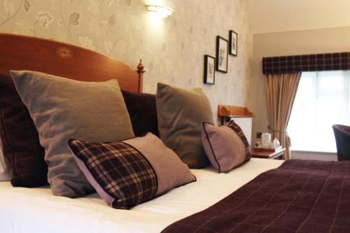 a bedroom with a bed with several pillows on it at Appleby Manor Hotel & Garden Spa in Appleby