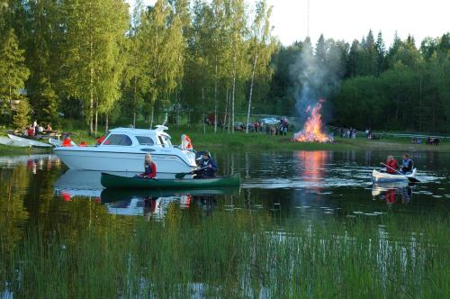 a group of people in boats in a lake with a fire at Hännilänsalmi Camping in Viitasaari