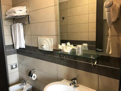 W łazience znajduje się umywalka, toaleta i lustro. w obiekcie Hotel Visagi w mieście Pompeje