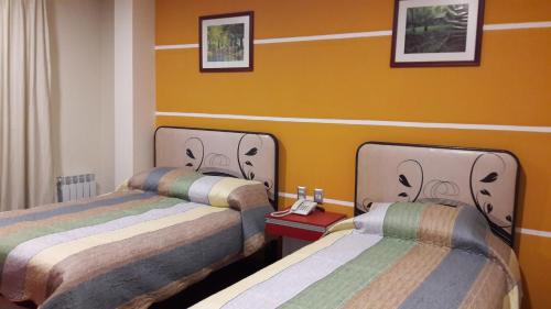 two beds in a room with yellow walls at Apart Serma Hotel in Potosí