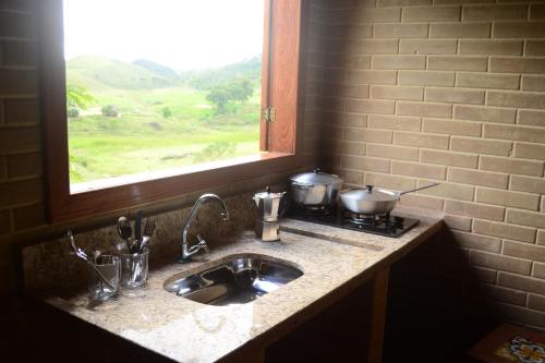a kitchen counter with a sink and a window at Espaço Puri in Divino de São Lourenço