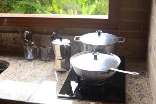 - une cuisinière avec 2 casseroles et des poêles dans l'établissement Espaço Puri, à Divino de São Lourenço