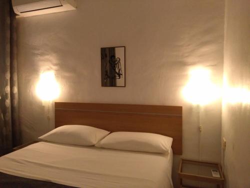 een slaapkamer met een bed met witte lakens en 2 verlichting bij Chalecito in La Manga del Mar Menor