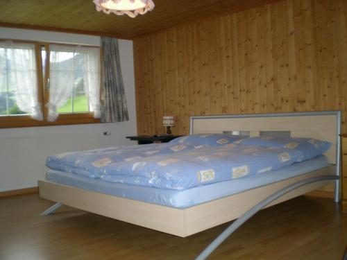 ein großes Bett in einem Zimmer mit Holzwänden in der Unterkunft Säntisblick in Urnäsch