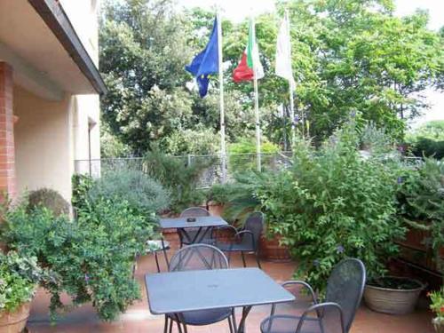 um pátio com duas mesas, cadeiras e bandeiras em Hotel Mirella em Castiglione della Pescaia