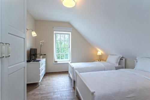 a white bedroom with two beds and a window at Green Hill Guest House in Berkovitsa