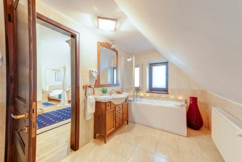 a bathroom with a tub and a sink and a mirror at Karlhof in Sebeş