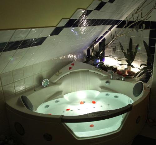 a bath tub in a room with a tile wall at Kőszeghegyalja Vendégház in Horvátzsidány