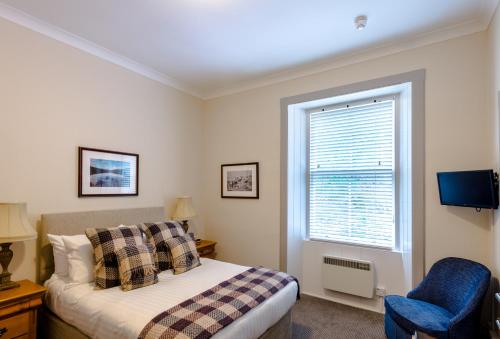 a bedroom with a bed, chair, desk and window at Inch Hotel in Fort Augustus