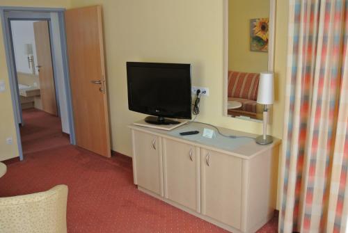 a room with a television on a cabinet with a mirror at Landhotel Stofflerwirt in Sankt Michael im Lungau
