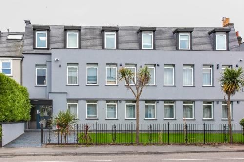 a gray building with palm trees in front of it at Hampton Suites Serviced Apartments in Kingston upon Thames