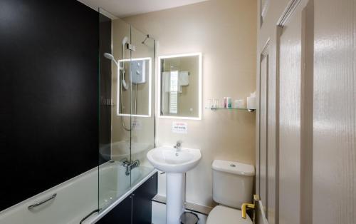 a bathroom with a toilet, sink, and mirror at Inch Hotel in Fort Augustus