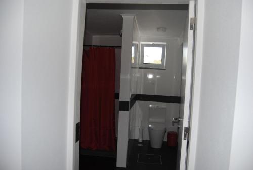 ein Badezimmer mit einem WC und einem roten Duschvorhang in der Unterkunft Casa da Malta in Livramento
