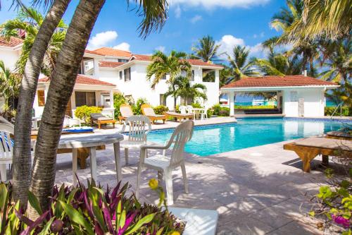 聖佩德羅的住宿－Tradewinds Paradise Villas，游泳池旁带桌椅的天井