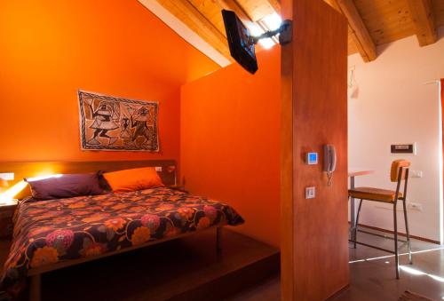 1 dormitorio con paredes de color naranja y 1 cama en una habitación en Lucciole per Lanterne, en Gorizia