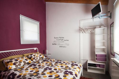 1 dormitorio con cama y pared púrpura en Lucciole per Lanterne, en Gorizia