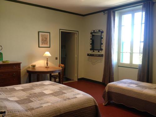 une chambre avec deux lits et une table et une fenêtre dans l'établissement Mas la Cigaliere, à Venasque