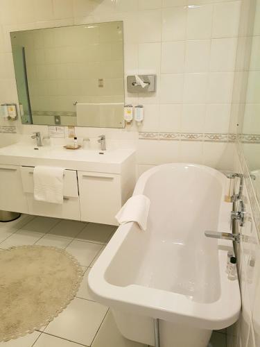 a white bathroom with a tub and a sink at Villa Castollini in Brenton-on-Sea