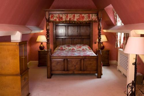 a bedroom with a canopy bed and two lamps at Cotswold Lodge Hotel in Oxford