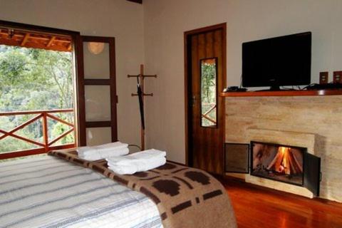 a bedroom with a fireplace and a television and a bed at Pousada Três Orelhas - Gonçalves MG in Gonçalves