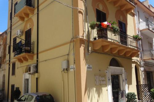 a yellow building with two balconies and a car at Monolocale La Chicca in Castellammare del Golfo