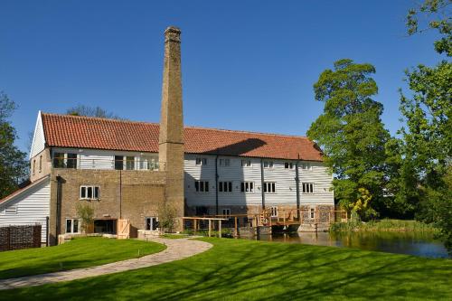 an old building with a tower and a river at Tuddenham Mill Luxury Hotel in Tuddenham