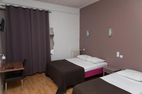 Cette petite chambre comprend deux lits et une table. dans l'établissement Le Pavillon, à Blois