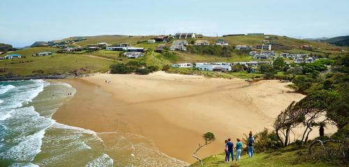 a group of people standing on a beach near the ocean at Uberkei in Coffee Bay